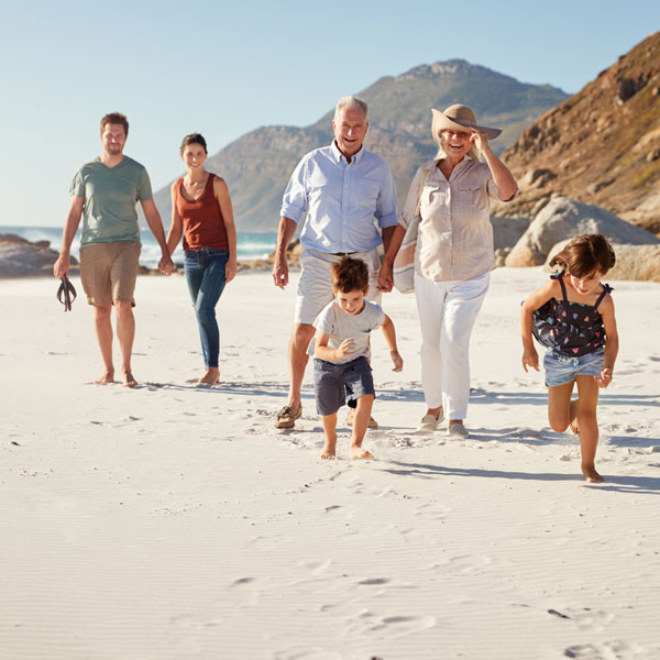 Grandparents and parents walking on beach with young children